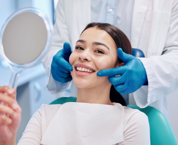 Patient smiling while holding small mirror