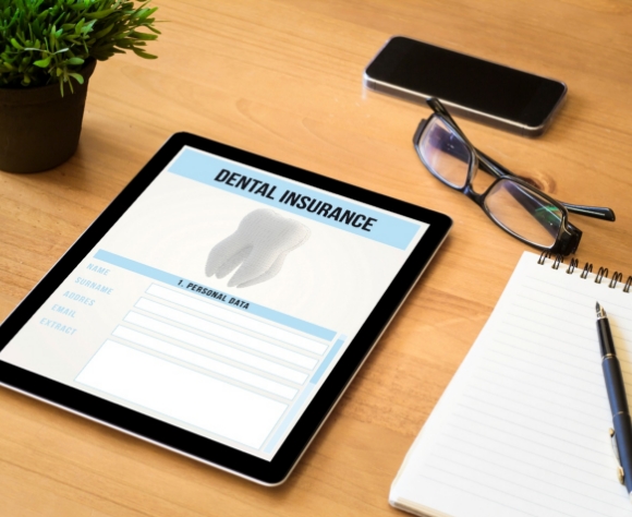 Dental insurance form on tablet next to desk supplies