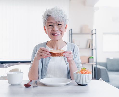 Older woman eating lunch and smiling with dentures