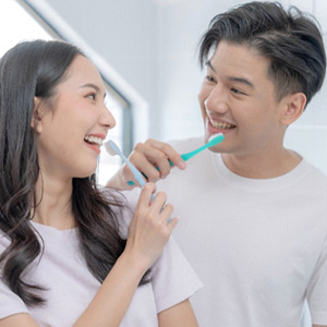 Man and woman smiling at each other during brushing routine