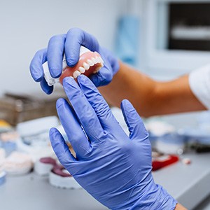 Dental technician holding a full arch of implant dentures