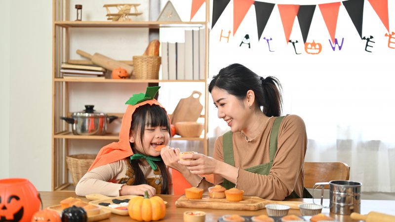 Patient with good oral health smiling with child eating Halloween cookies